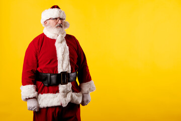 Fototapeta na wymiar Santa Claus pointing his eyes at a poster on a yellow background