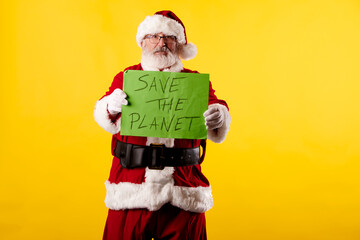 Fototapeta na wymiar Santa Claus with a Save the planet poster on a yellow background