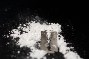 Razor Blade on drug powder on reflection black background.Copy space.