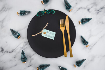 plant-based label on top of black dining plate with Christmas decorations all around on marble...
