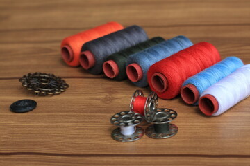 Spools of Thread, Bobbins, and Buttons on Wooden Surface – Sewing Supplies Close-Up