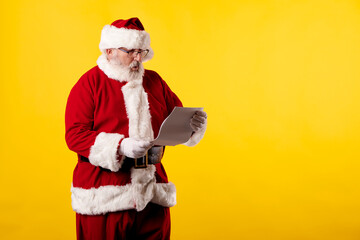 Fototapeta na wymiar Santa Claus reading a letter on yellow background
