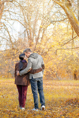 Naklejka na ściany i meble Autumn Caucasian Couple Standing Face-to-Face in a Park Full of Sun. Casual Style in Autumn Colors. Full-length. Fall Park Background