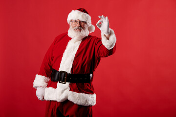 Fototapeta na wymiar Santa Claus making OK gesture on red background