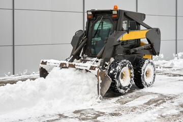 A snowplow tractor clears snow from the house territory. Copy space.