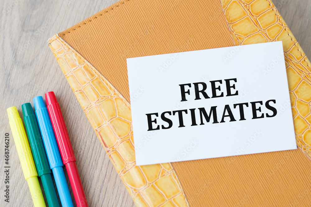 Poster card with text free estimates on a yellow notepad on the table next to colored markers