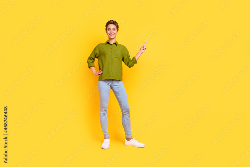 Wall mural Photo of promoter lady arm hip direct finger empty space wear green shirt jeans shoes isolated yellow color background