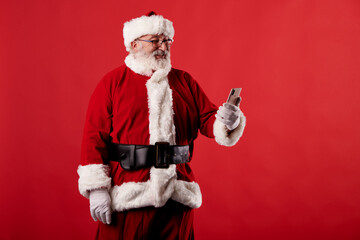 Fototapeta na wymiar Santa Claus using a mobile phone on red background