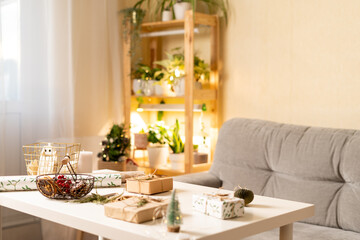 Stylish Christmas room interior with Christmas light and gifts on table, preparing for Christmas holiday. Cozy home. Background with copy space.
