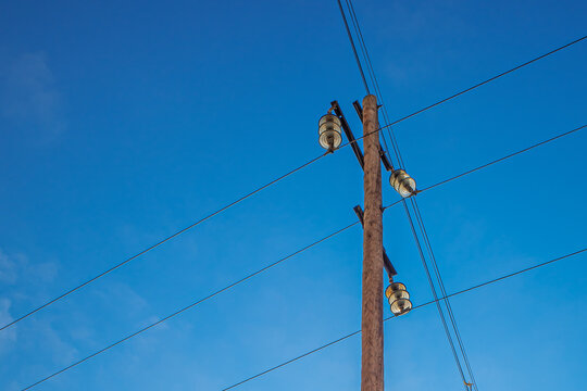 The upper part of the power line support against the blue sky
