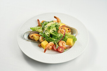 Shrimp and mussel salad, mango in a white plate on a tablecloth