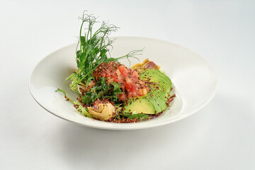 Salad with artichokes, tomatoes, quinoa and avocado in a white plate. Superfood