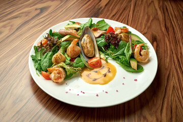 Salad with seafood, shrimps and mussels, orange dressing in a white plate on a wooden background