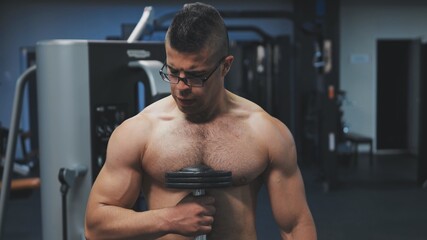 Fototapeta na wymiar Muscular arab man training with dumbbells in the gym.