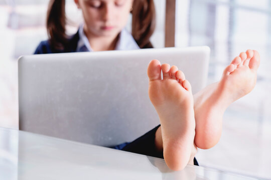 Humorous image of beautiful young business girl working in office with bare feet. Selective focus on feet.