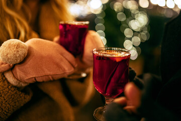 Close-up woman's hands in winter mittens with hot cup of hot mulled wine. Holidays, traditions,...