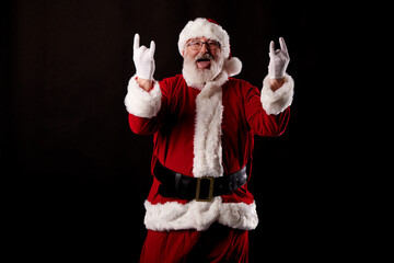 Fototapeta na wymiar Santa Claus making a rocker gesture on black background