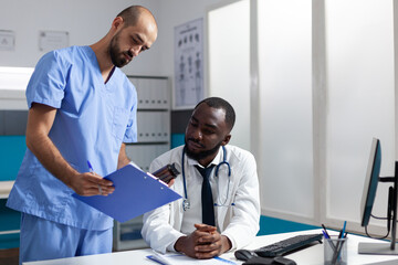 Medical team of practitioners analyzing disease symptoms discussing healthcare treatment working in hospital office. Doctor checking medicine prescription during clinical appointment