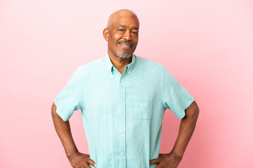 Cuban senior isolated on pink background posing with arms at hip and smiling