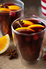 Glass of hot mulled wine with spices on wooden background