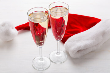 Two glasses of champagne and a Santa cap, light background. Christmas party concept