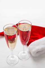 Two glasses of champagne and a Santa cap, light background. Christmas party concept
