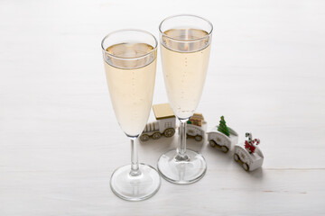 Two champagne glasses and Christmas ornaments on a light background. New year party concept