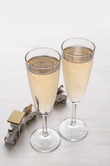 Two champagne glasses and Christmas ornaments on a light background. New year party concept