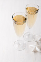 Two champagne glasses and Christmas ornaments on a light background. New year party concept