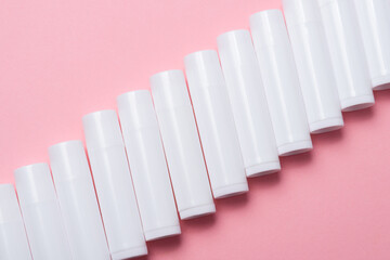 Lot of white plastic lip gloss tubes on pink background