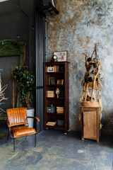 interior shot in the loft studio. an unusual decorative wall, A bookcase full of books. a chic gray sofa. Arrangement of furniture. Unusual interior decorations.