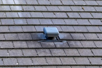A portrait of a roof vent on a slate roof on a house. This small chimney like object is used as a...