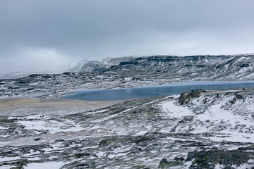 Iceland blue lake Heidharvatn with snow covered mountains and fog