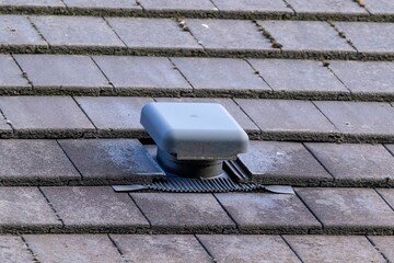 A close up portrait of a roof vent on a slate roof on a house. This small chimney like object is...
