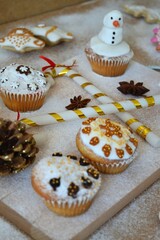 Christmas composition: Christmas cupcakes decorated with icing and surrounded by cinnamon sticks and star anise on a background of powdered sugar