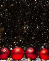 Christmas decorations composition view of four red evening balls with red glitter snowflakes on it on dark background with silver and gold colors bokeh Holiday concept with copy space on top