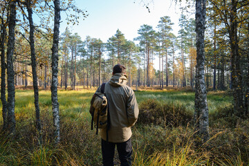 A man traveler walks through the woods. Beautiful wild nature landscape in forest. Hiking journey on tourist trail. Outdoor adventure. Travel and exploration. Healthy lifestyle, leisure activities