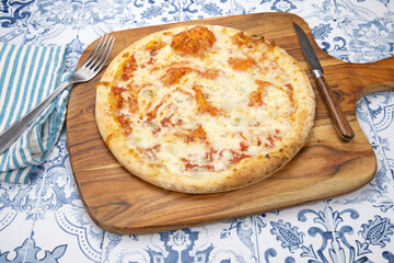 Pizza italienne fraîche entière avec des tomates sur une planche de bois