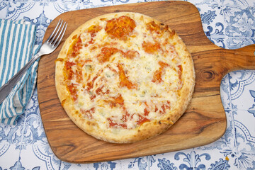 Pizza italienne fraîche entière avec des tomates sur une planche de bois