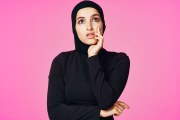 cheerful muslim woman in black hijab posing fashion pink background
