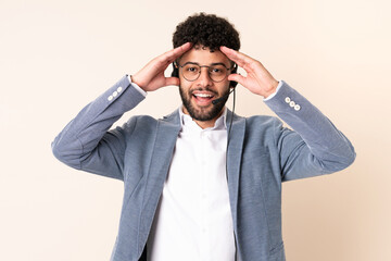 Telemarketer Moroccan man working with a headset isolated on beige background with surprise expression