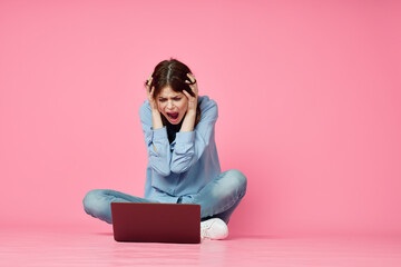 woman sitting on floor with laptop shopping entertainment pink background