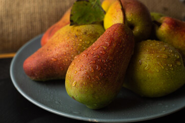 Blurred image of juicy, ripe pears in a gray plate against a textured background.