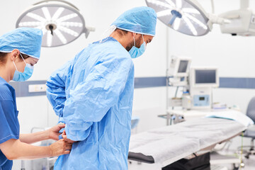 Krankenschwester hilft Chirurg beim Kittel anziehen
