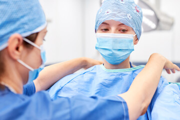 Ärztin als Chirurgin beim Schutzkleidung anziehen