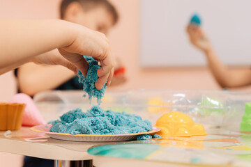 kinetic sand. children's hands play with multi-colored polymer sand.
