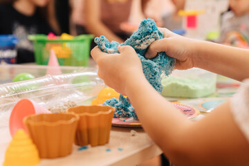 kinetic sand. children's hands play with multi-colored polymer sand.