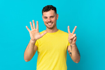 Fototapeta premium Young caucasian handsome man isolated on blue background counting seven with fingers