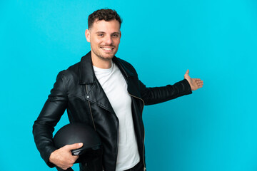 Caucasian man with a motorcycle helmet isolated on blue background extending hands to the side for inviting to come