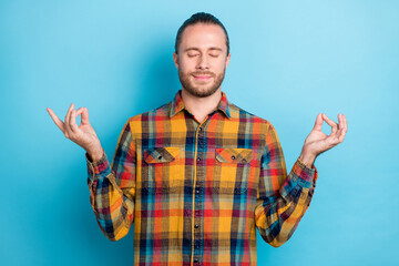 Photo of sleepy young brunette guy do yoga wear checkered shirt isolated on blue color background